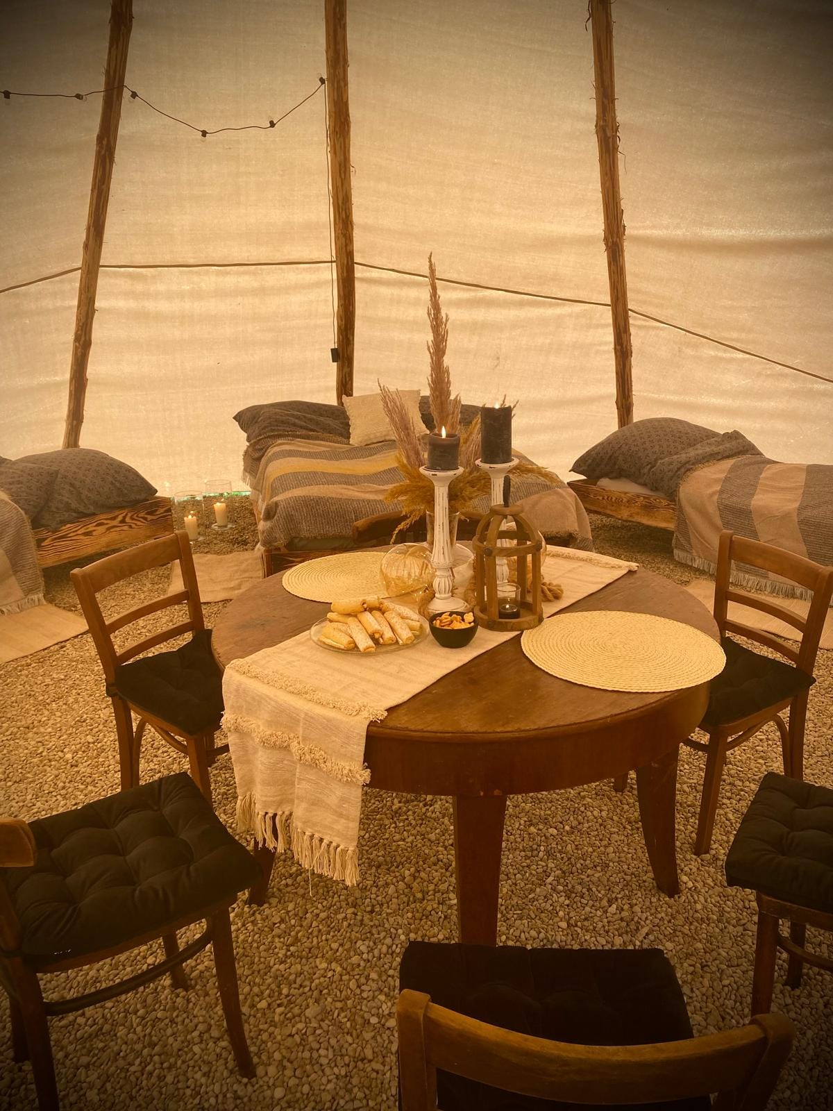 Klimatyczne wnętrze tipi — stół, świece, kanapy